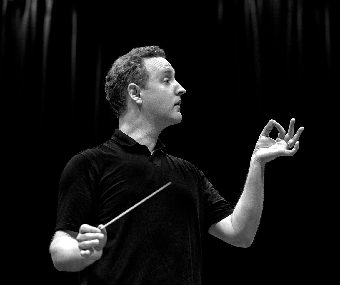 Michael Francis conducting in profile, shaping a phrase with his hand