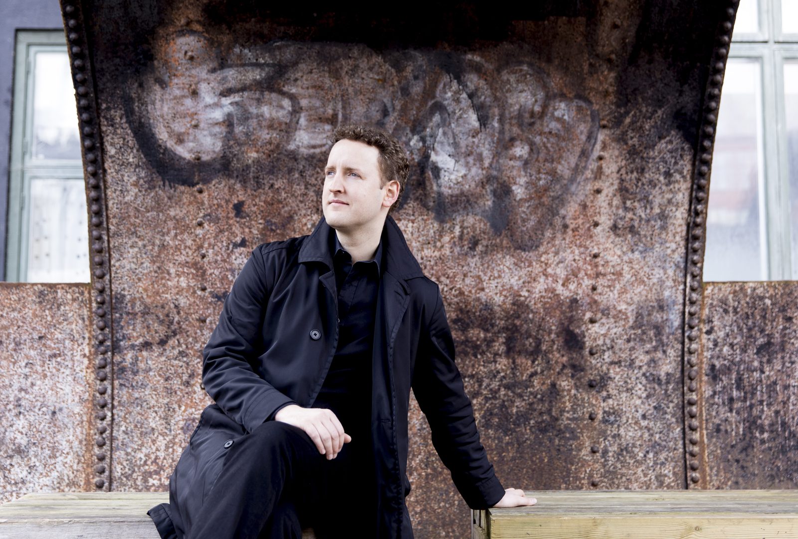 Michael Francis seated against a weathered metal wall