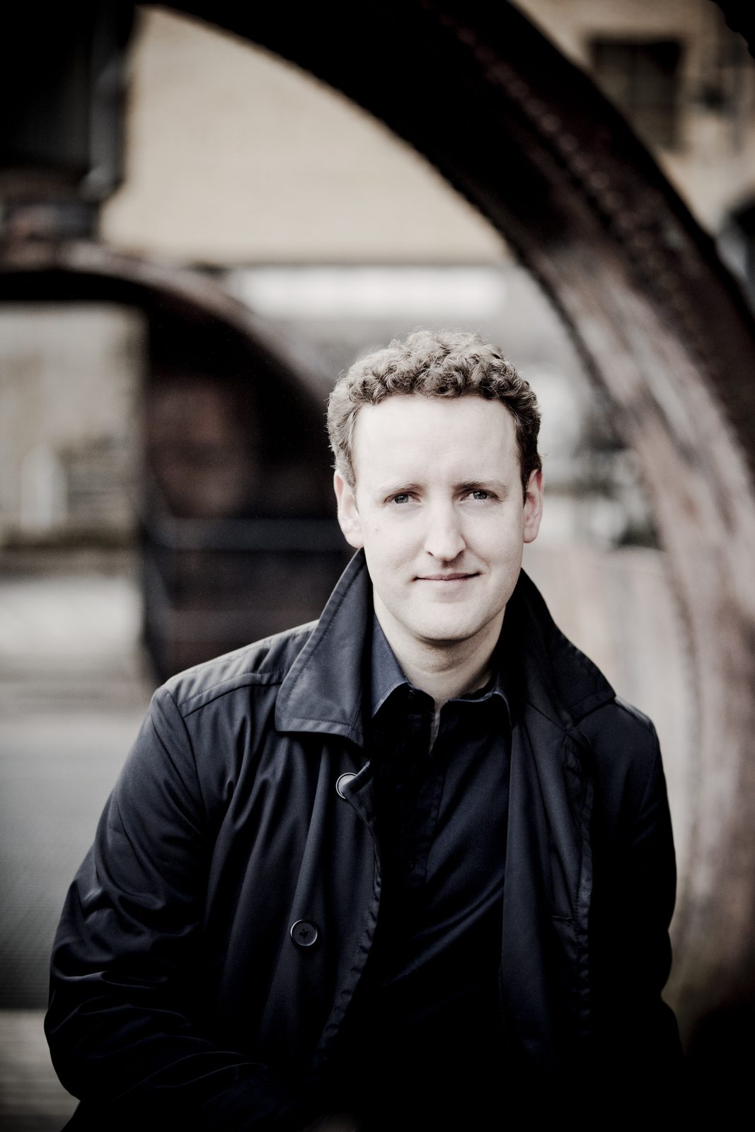 Michael Francis under an archway in a dark coat
