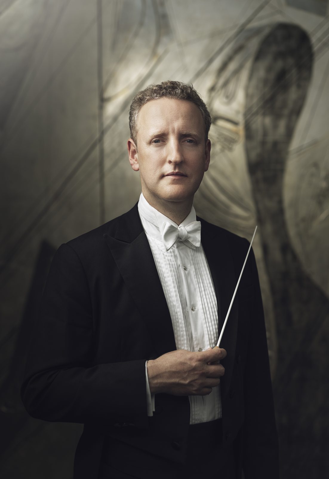 Michael Francis in white tie and tails holding a baton